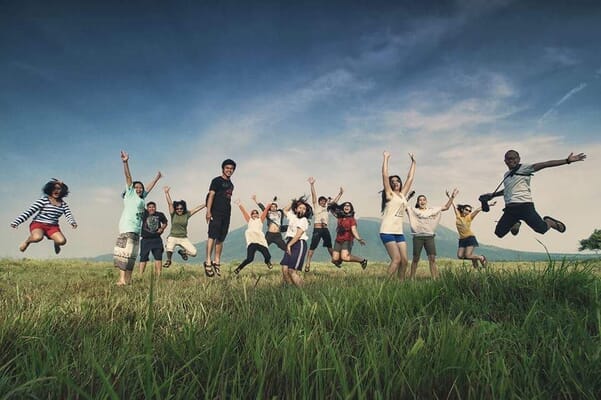People jumping for joy in grass field
