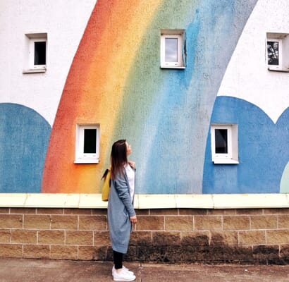womwoman looking up at rainbow wall