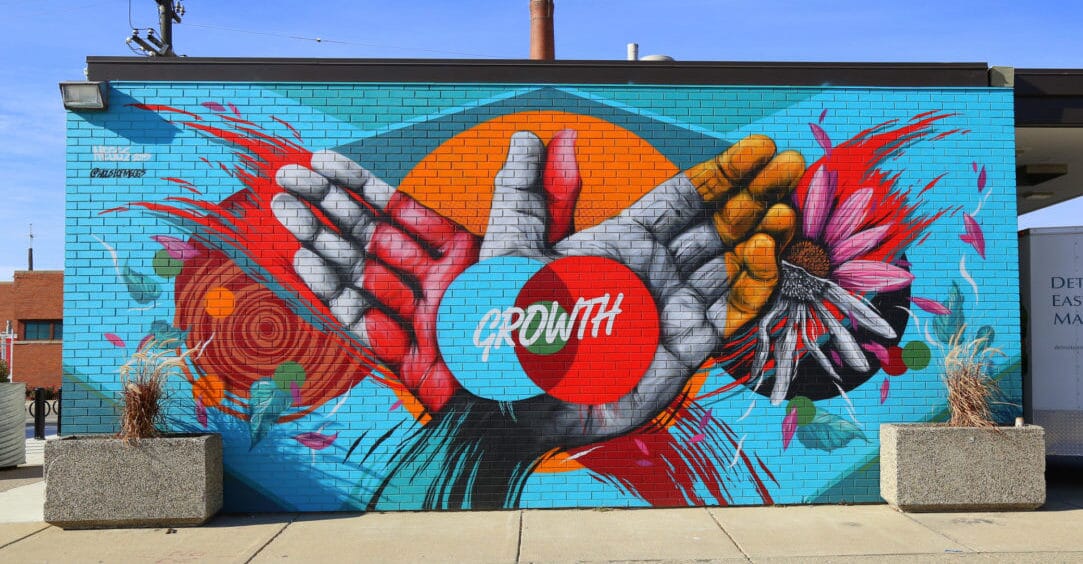 Painting on brick wall depicting hands and word "growth"